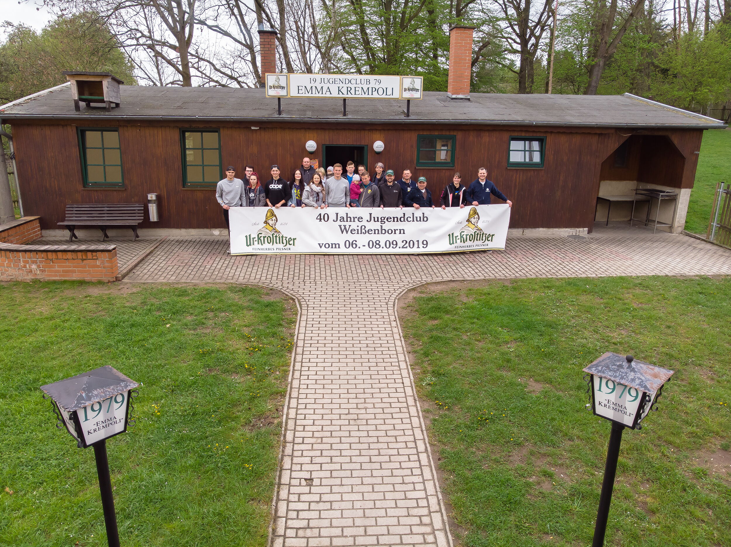 Eine Gruppe Jugendlicher steht vor einem Vereinsgebäude und hält ein Banner zum 40-jährigen Jubiläum des Jugendclubs.