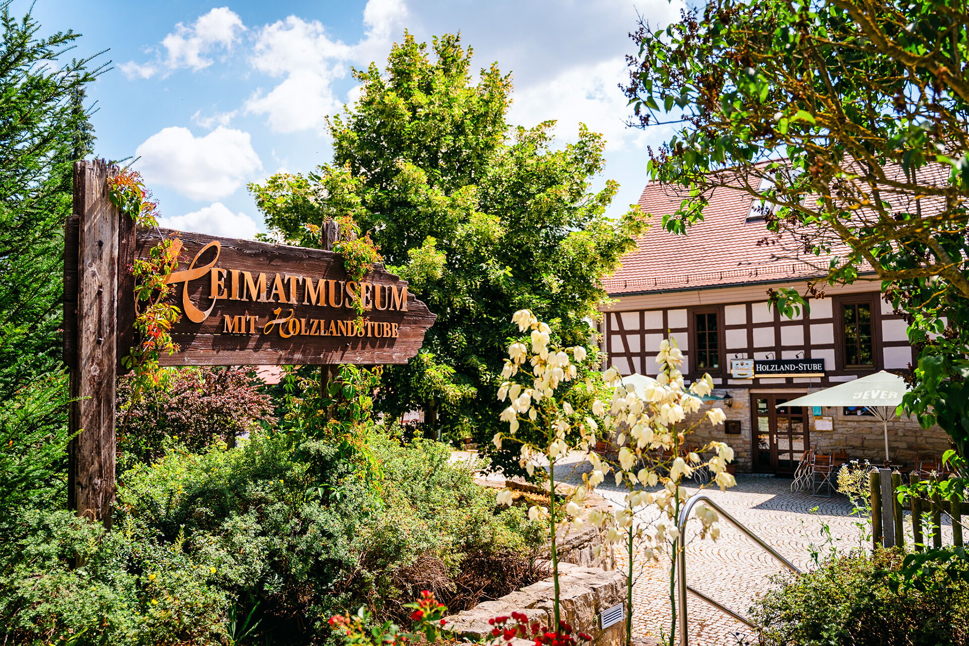 Das idyllische Heimatmuseum von Bad Klosterlausnitz mit Fachwerkhaus und üppigem Garten lädt bei sonnigem Wetter zur Entdeckung ein.