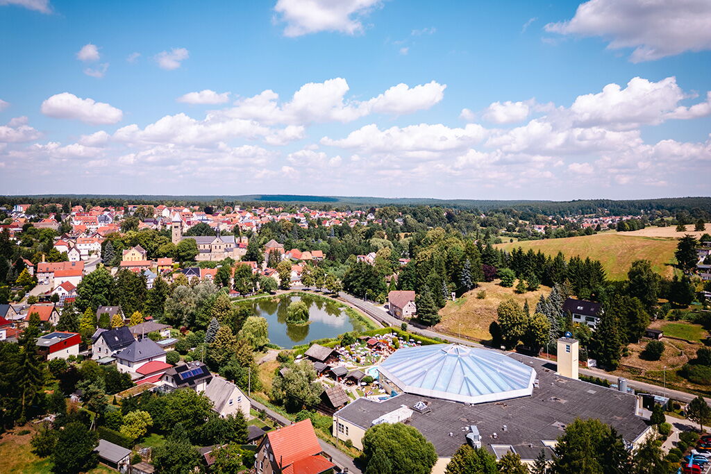 Die Luftaufnahme zeigt Bad Klosterlausnitz mit einem großen Gebäude im Vordergrund und einer malerischen Landschaft im Hintergrund.
