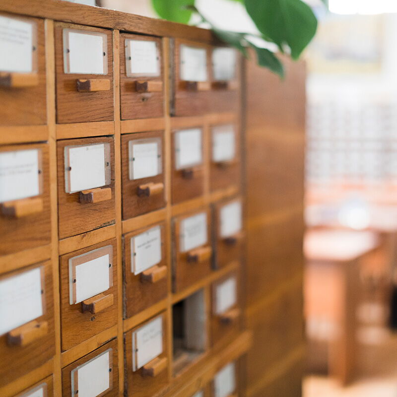 Holzschubladen eines Karteikastens im Gemeindearchiv von Bad Klosterlausnitz, mit Fokus auf die Beschriftungen.