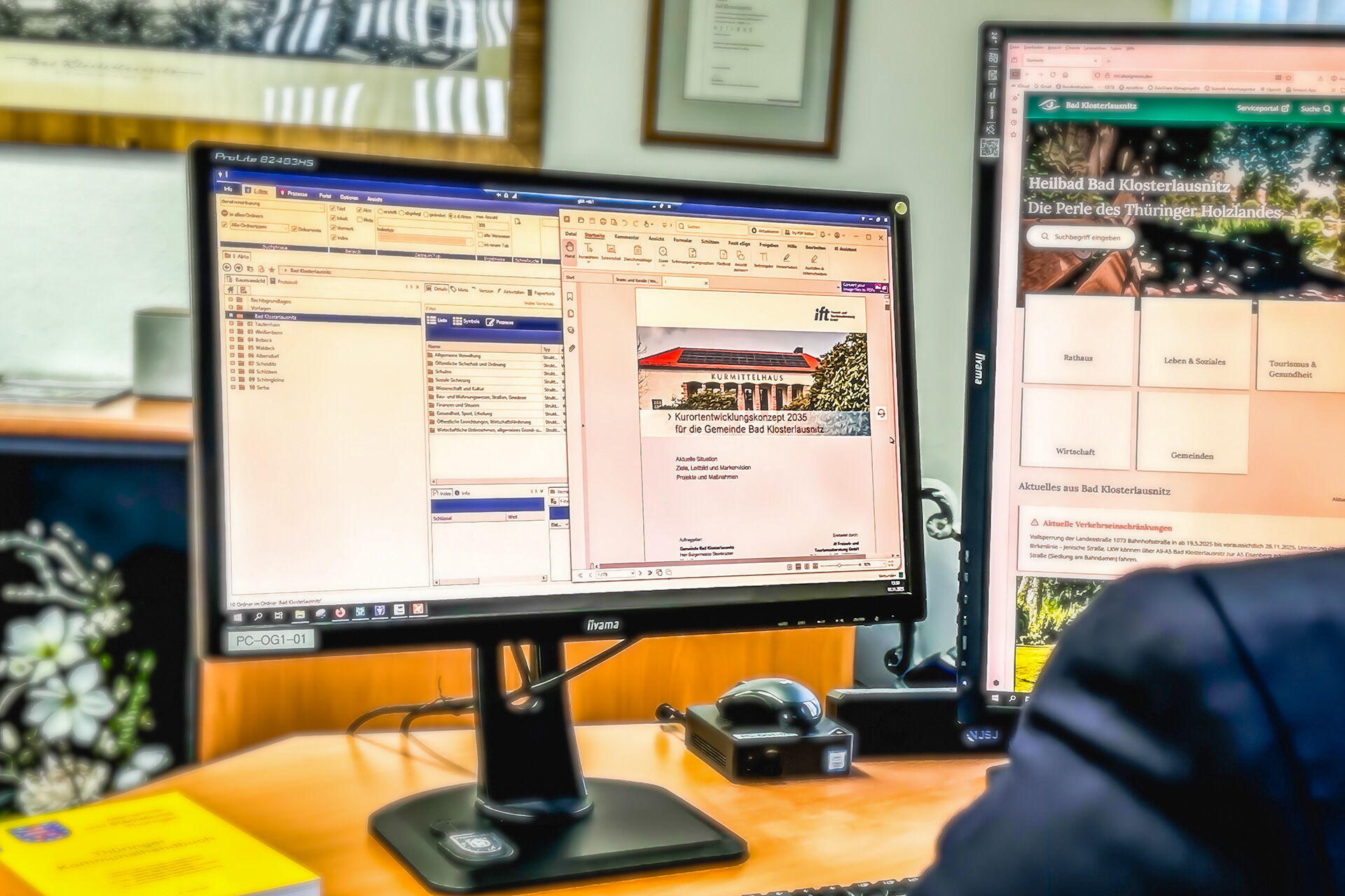 Zwei Computerbildschirme zeigen Dokumente und Webseiten, darunter ein Kurortentwicklungskonzept für Bad Klosterlausnitz.