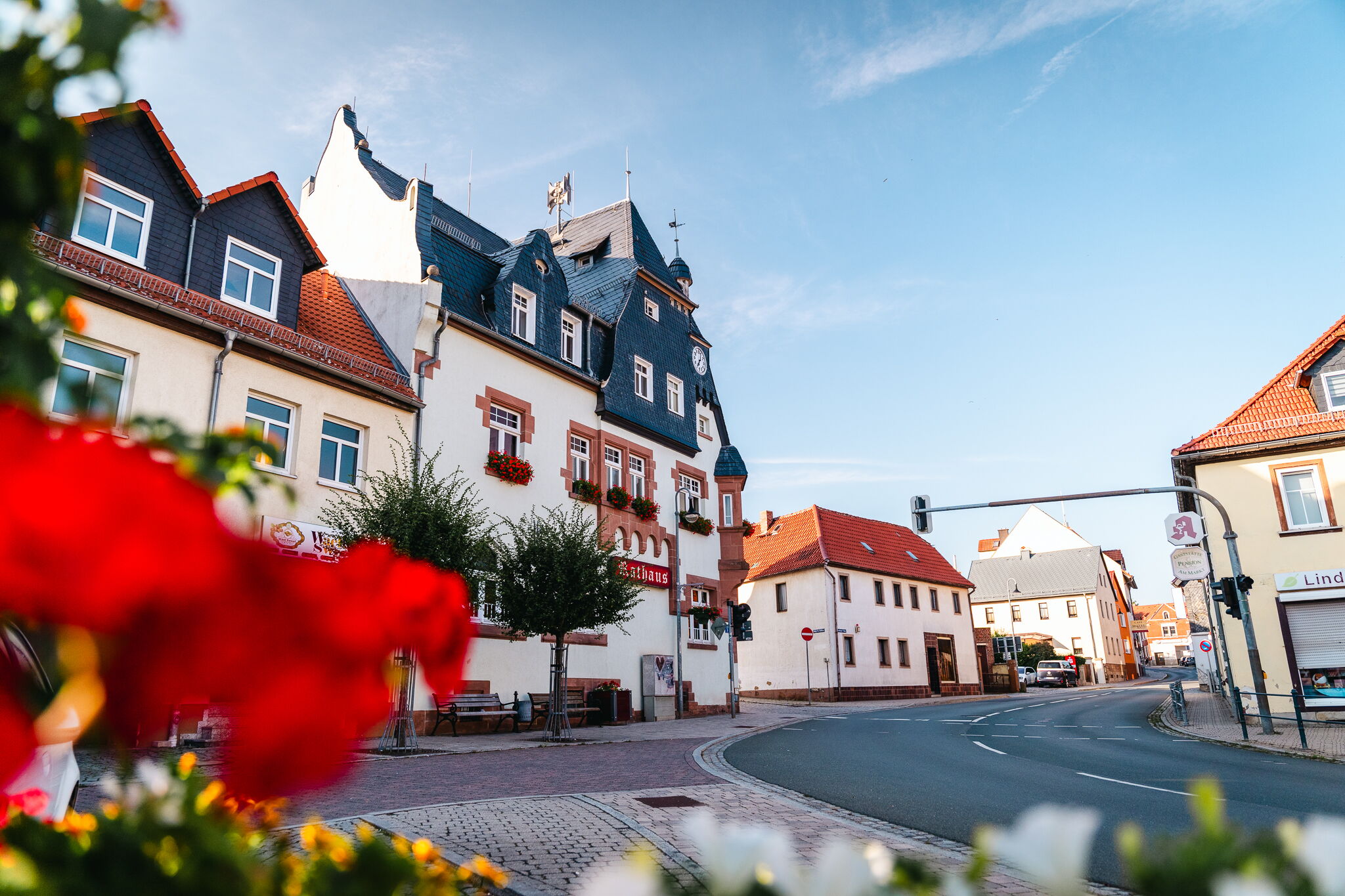 Das historische Rathaus und farbenfrohe Blumen schmücken die Hauptstraße von Bad Klosterlausnitz an einem sonnigen Tag.