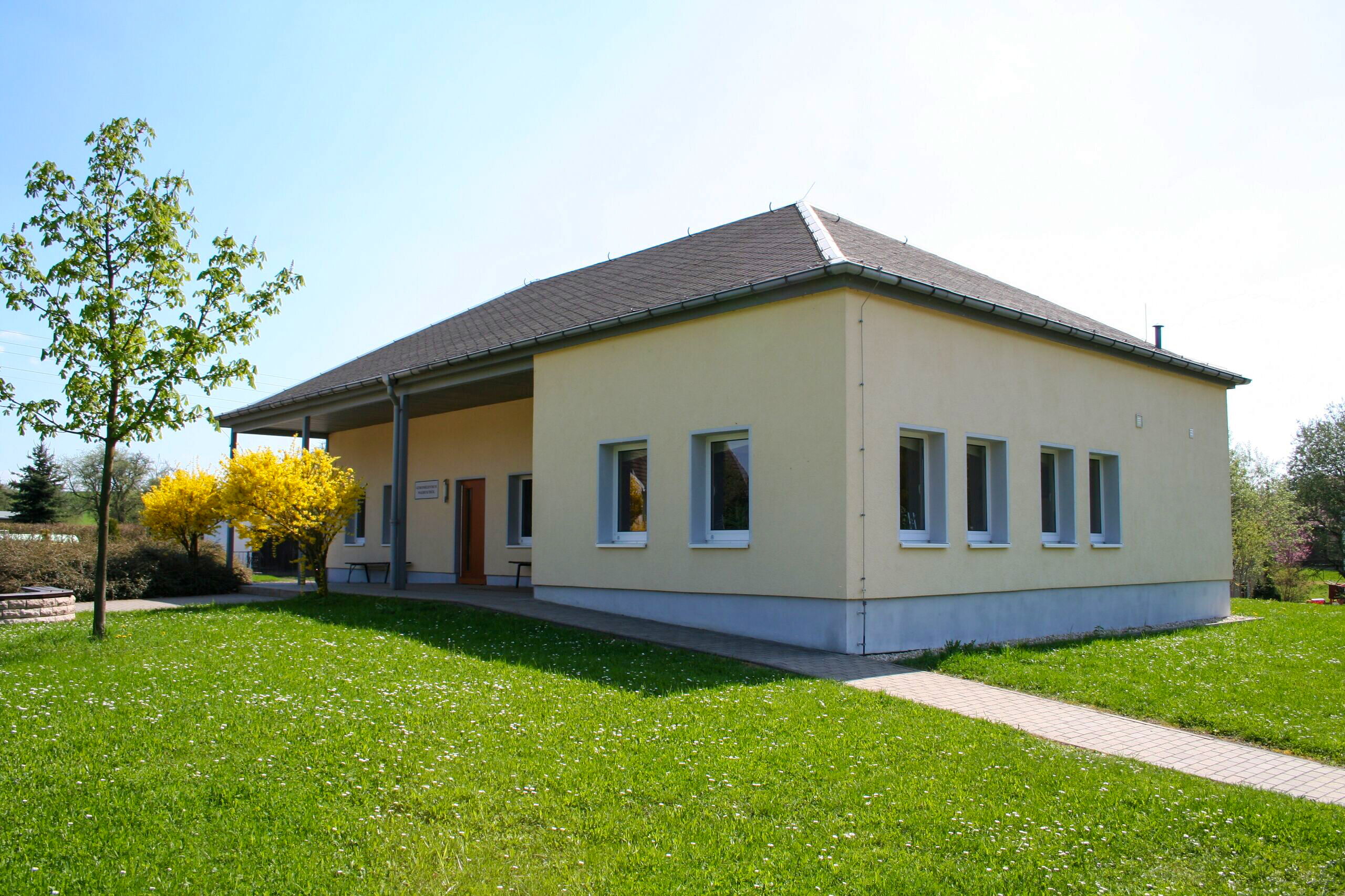 Modernes Gemeindezentrum in Waldeck inmitten eines gepflegten grünen Rasens unter klarem Himmel.