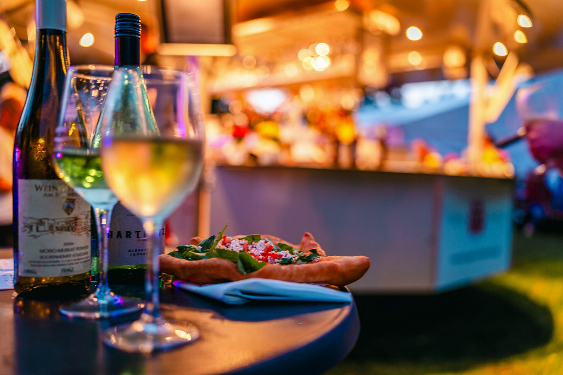 Ein Tisch mit Weinflaschen, gefülltem Gebäck und Gläsern bei einem stimmungsvollen kulinarischen Event.