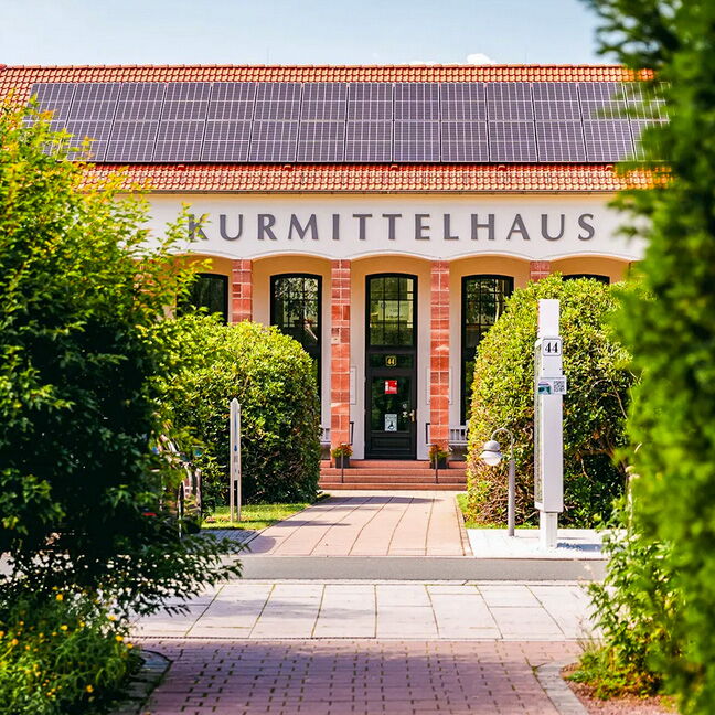 Das Kurmittelhaus mit Solarpanelen auf dem Dach ist von üppigem Grün umgeben und lädt zur Entspannung ein.