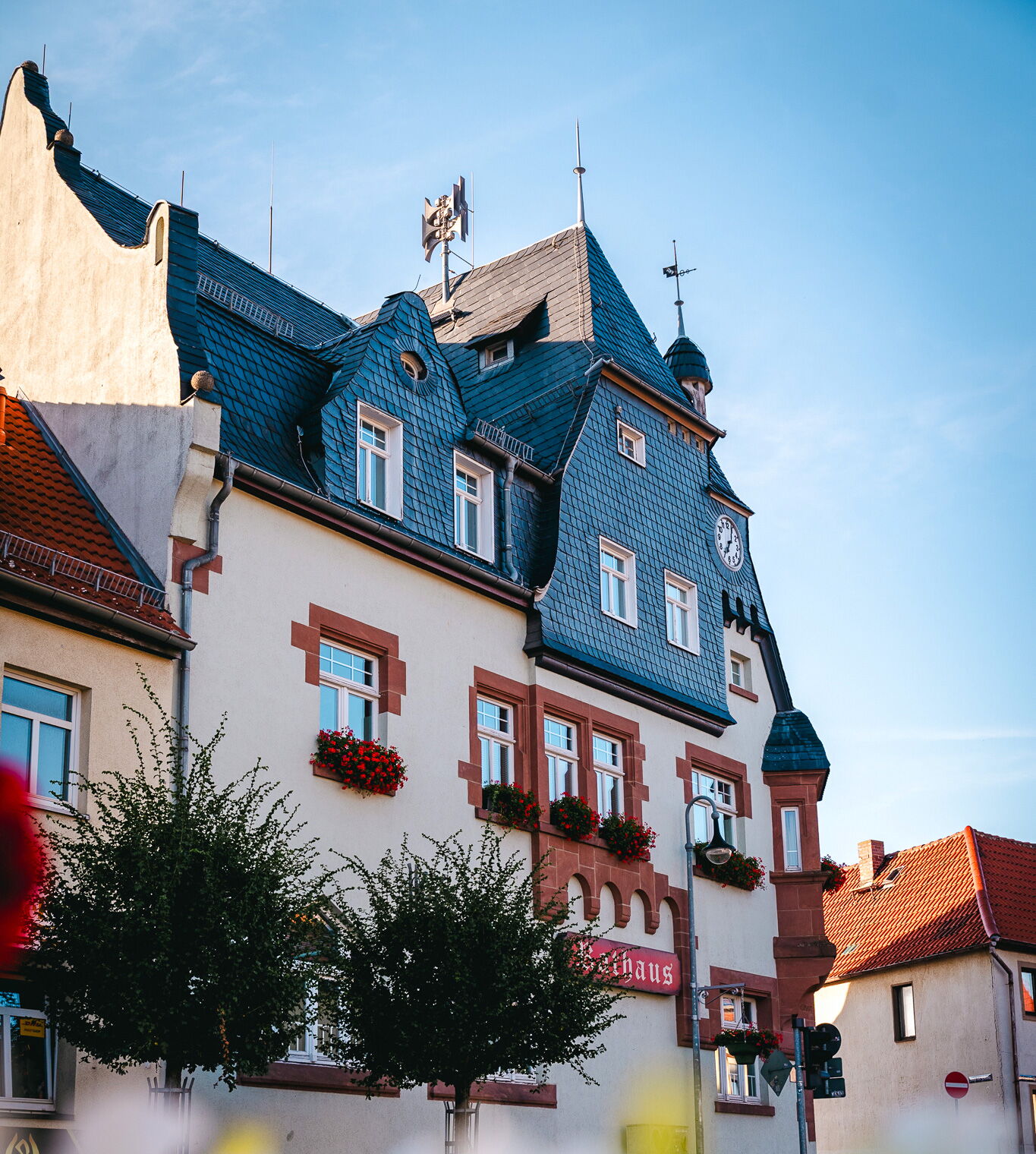 Das historische Rathaus von Bad Klosterlausnitz erstrahlt unter einem klaren blauen Himmel mit blühenden Blumen an den Fenstern.