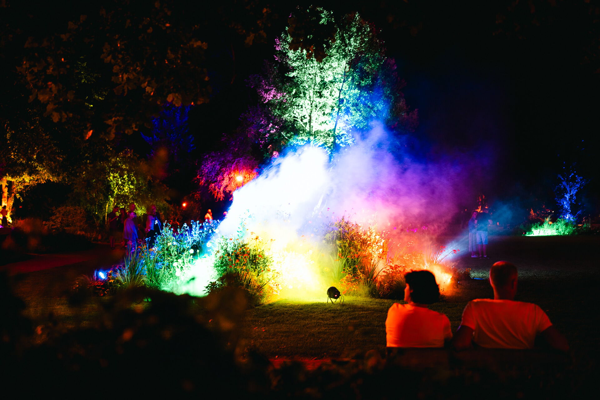 Ein Paar genießt abends in Bad Klosterlausnitz ein beleuchtetes Farbenspiel im Park.