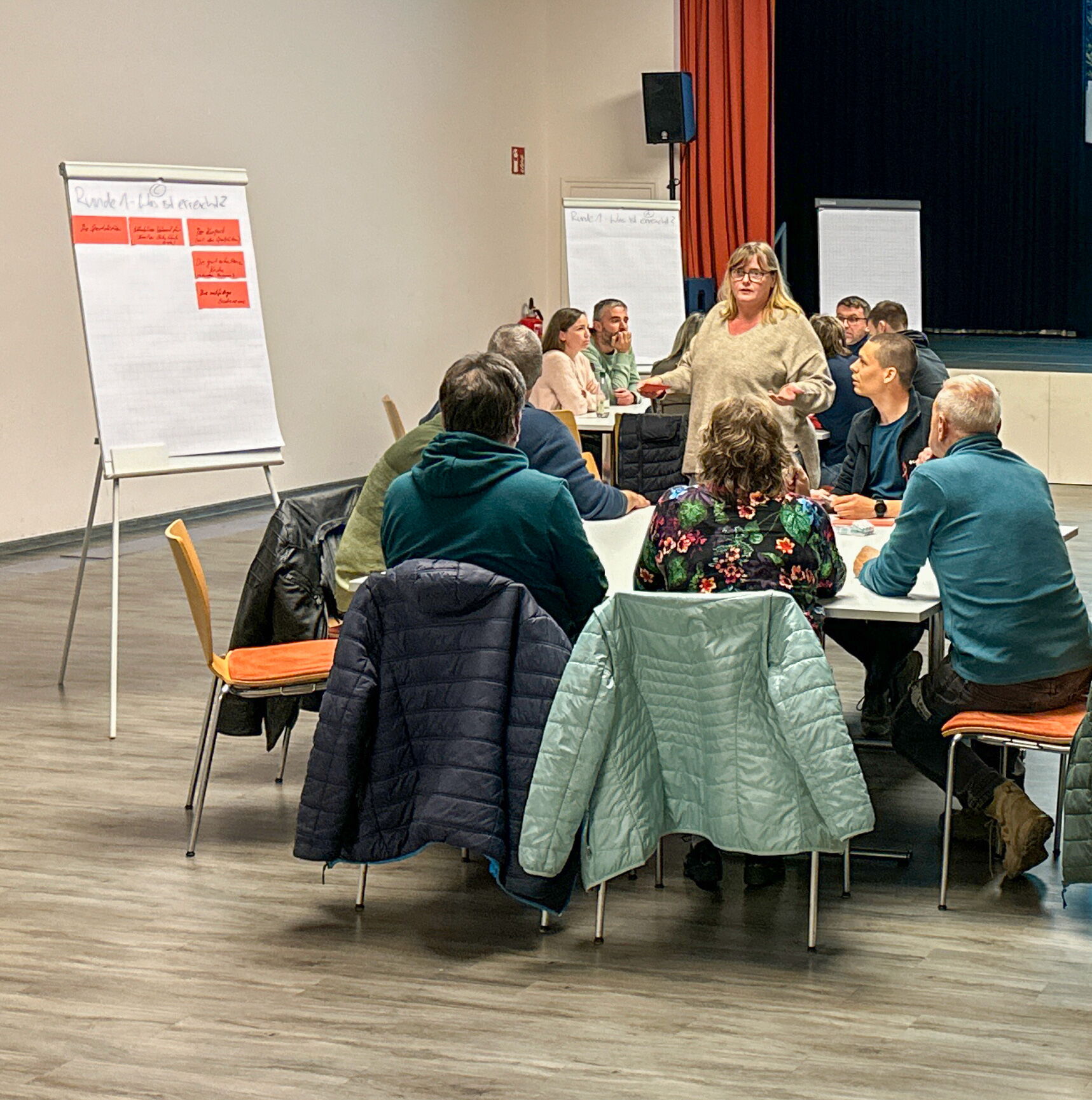 Menschen diskutieren bei einem Bürgerdialog am 5. November 2024 um einen Tisch in einem Konferenzraum.