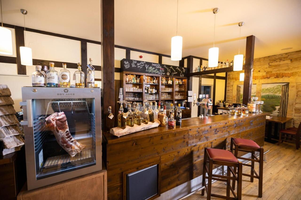 Gemütliche Bar in der Pension Friedrichshof mit rustikalem Dekor, gut bestückter Theke und einem Fleischstück im Dry Ager.