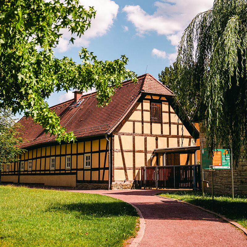 Die Festscheune, ein traditionelles Fachwerkgebäude unter blauem Himmel in Bad Klosterlausnitz, umgeben vom idyllischen Kurpark.